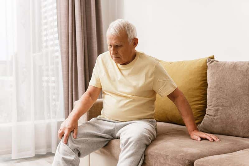 Older man with knee pain alone at home